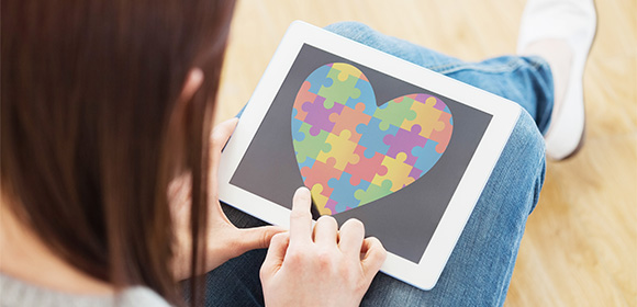 person using tablet to interact with colorful heart puzzle graphic showing creativity and fun 19 puzzle pieces concept